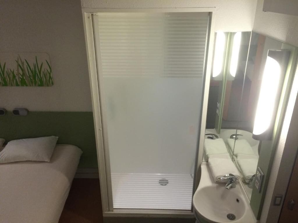 Un baño pequeño y privado con ducha, inodoro y lavamanos.