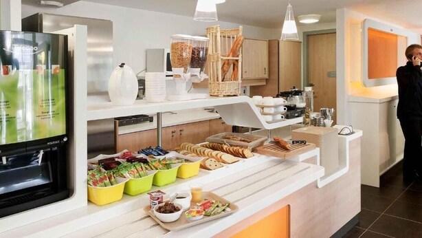Una cocina moderna con refrigerador integrado, cafetera y diversos productos para el desayuno sobre la encimera.