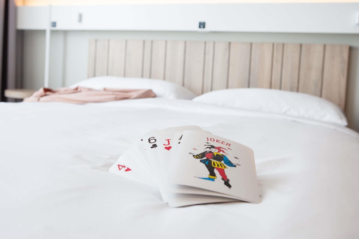 Una cama bien hecha con ropa de cama blanca y un cabecero con listones verticales.