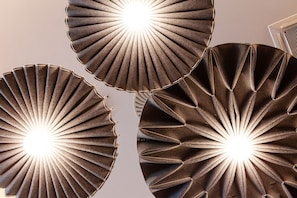Drie wandlampen, rond, met plooien en een centraal lichtgevend element.