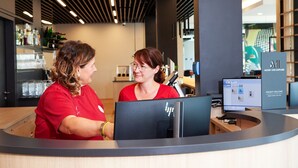 Een receptiebalie met twee medewerkers, een computer en een bordje met de tekst 'ACCOR LIVE LIMITLESS'.