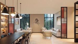 A modern interior with a long dining table, two sofas, and a large window. - Ibis Mumbai Bkc (Mumbai)
