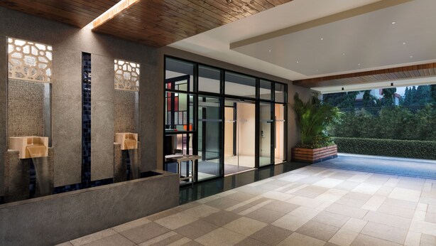 A modern lobby with a tiled floor, a reception desk, and a large window overlooking a garden. - Ibis Mumbai Bkc (Mumbai)