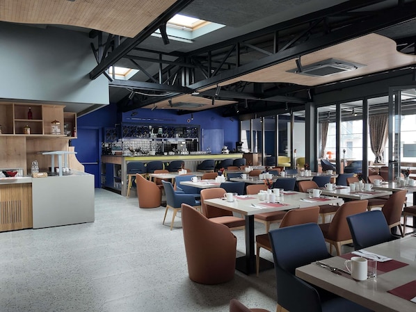 A modern restaurant with a bar area, seating, and a kitchen in the background. - Ibis Styles Ankara (Ankara)