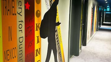 A hallway with a wall featuring travel-themed decorations and a silhouette of a person.