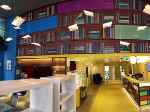 A modern library with bookshelves, a reception desk, and a yellow carpet. - Ibis Styles Ankara (Ankara)