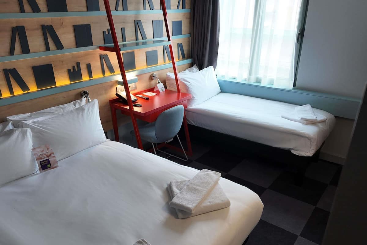 A hotel room with two beds, a desk, and a chair.