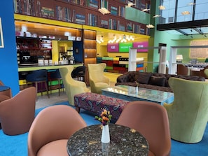 A modern library with bookshelves, a coffee bar, seating areas, and a colorful interior. - Ibis Styles Ankara (Ankara)