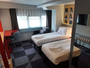 A hotel room with two beds, a desk, a chair, a TV, and a window with curtains. - Ibis Styles Ankara (Ankara)