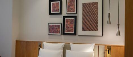 Habitación de hotel con una cama grande, cabecero de madera y una pared con obras de arte enmarcadas.