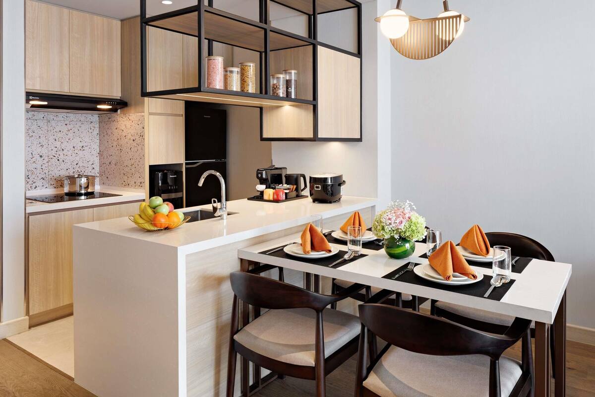 A modern kitchen with a central island, built-in appliances, and a dining area with a table set for two.
