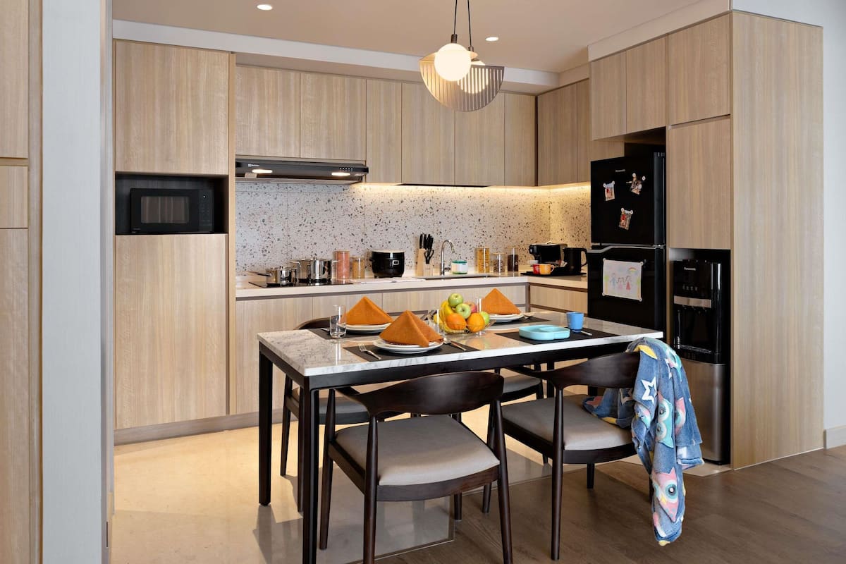 A modern kitchen with wooden cabinetry, a built-in microwave, a gas stove, and a black refrigerator.