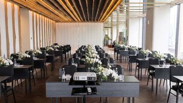 Une salle de conférence avec des rangées de tables, chacune équipée d’un projecteur et agrémentée de compositions florales.