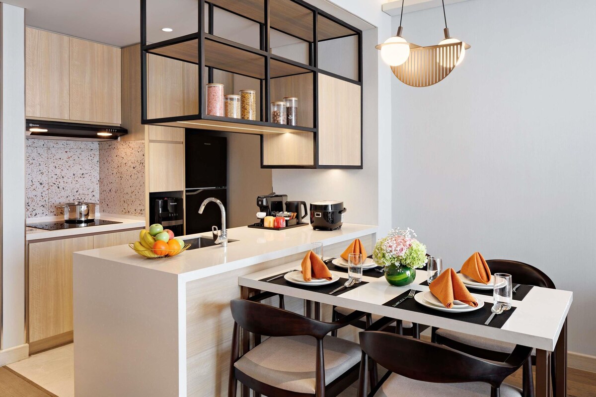 A modern kitchen with a central island, built-in appliances, and a dining area with a table set for two.