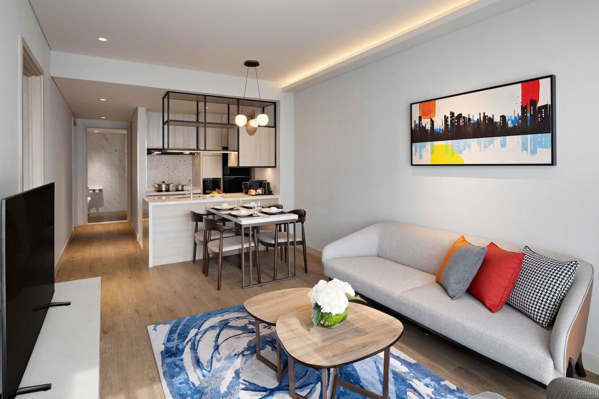 A modern living room with a sofa, a coffee table, and a dining area with chairs.