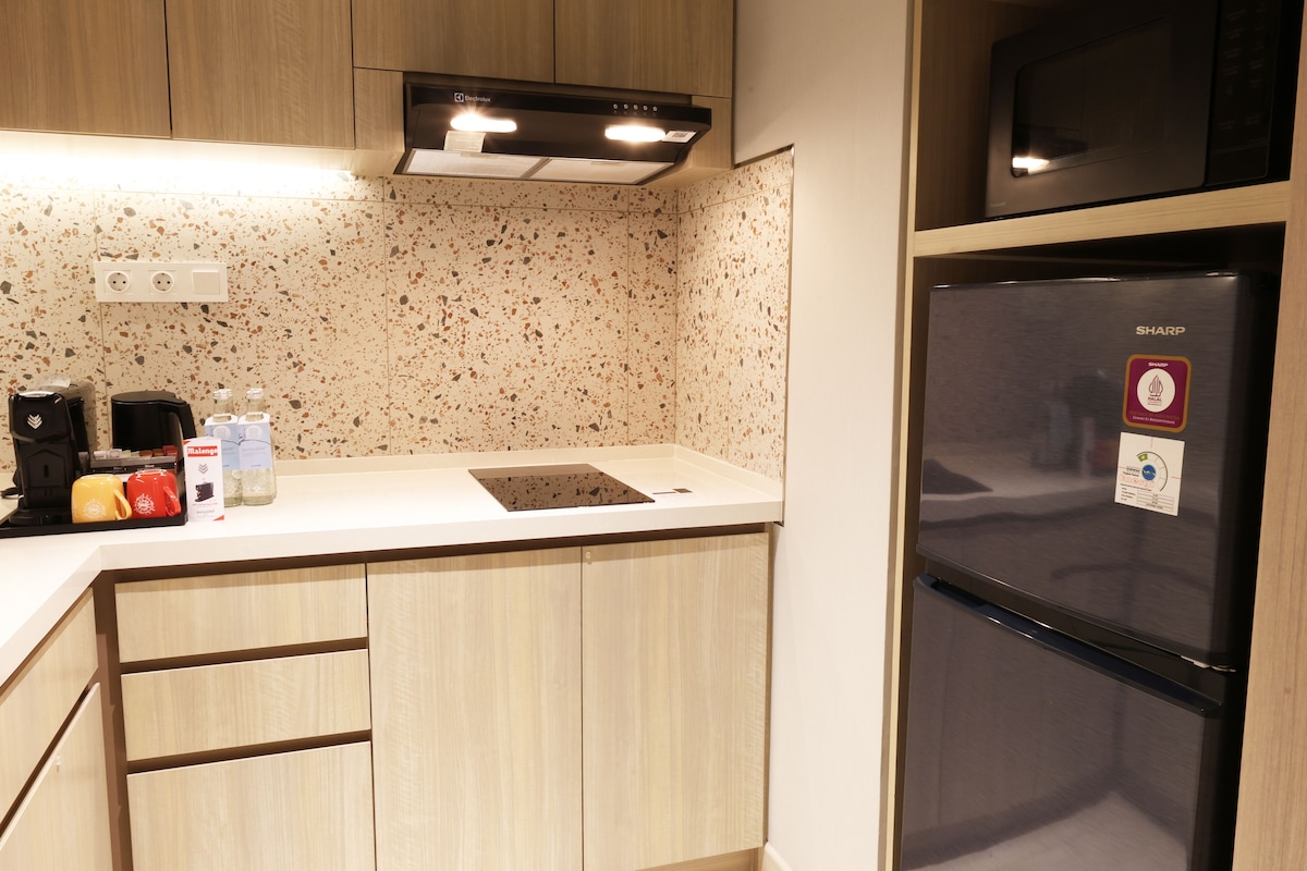 Una cocina equipada con una encimera, microondas, refrigerador y cafetera.