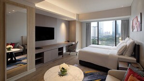 Una habitación de hotel moderna con una cama grande, un escritorio, un televisor y vistas a la ciudad.