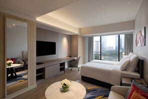 Una habitación de hotel moderna con una cama grande, un escritorio, un televisor y vistas a la ciudad.