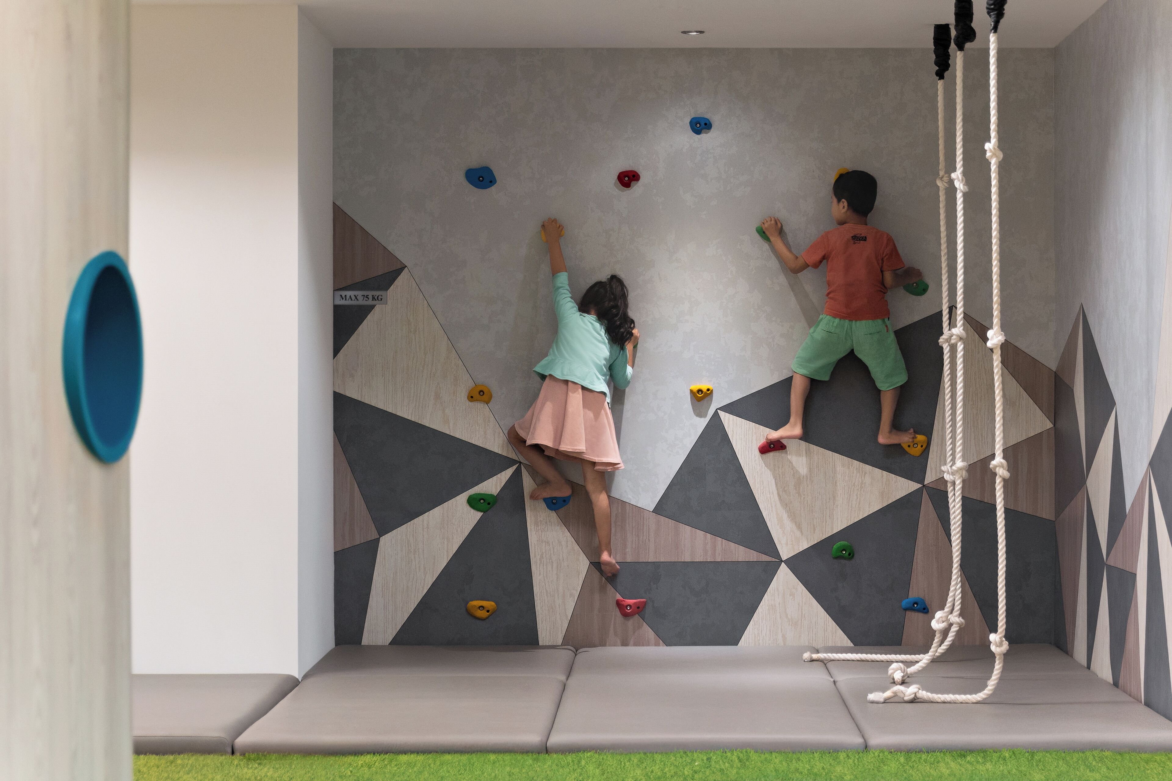 Un mur d’escalade orné de motifs géométriques et doté d’une zone d’escalade avec cordes.