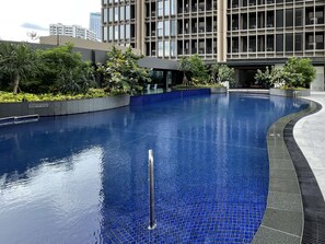 A swimming pool with a blue tiled bottom, surrounded by greenery and modern buildings. - Swissôtel Living Jakarta Mega Kuningan (Jakarta)