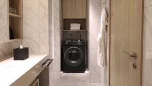 Un baño pequeño con lavadora, un perchero y un armario de madera con estantes.