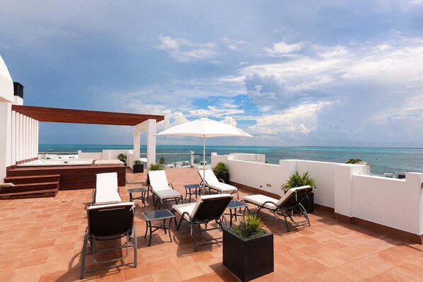 Eine Dachterrasse mit Pool, Liegestühlen und Blick auf den Ozean.