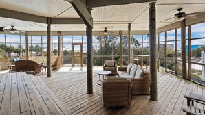 A covered outdoor area with wooden flooring, wicker furniture, and ceiling fans. - Huge 6 Bdrm/6+ Ba Private GF Home, Pool, Dune Walkover, Easy Access, Gulf Views (Gulf Shores)