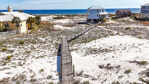 A beachside property with a wooden boardwalk leading to a large house with multiple levels. - Huge 6 Bdrm/6+ Ba Private GF Home, Pool, Dune Walkover, Easy Access, Gulf Views (Gulf Shores)