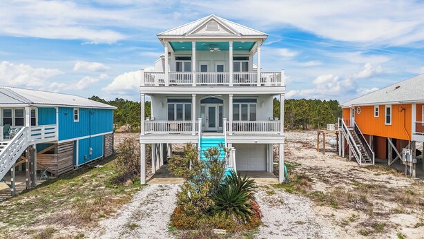 A two-story beachfront house with a balcony, a swimming pool, and a staircase leading to a deck.