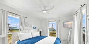 A bedroom with a bed, a ceiling fan, a TV, and windows with curtains. - Updated, budget friendly 4br/2ba beach home. Steps to the beach- gorgeous views. (Gulf Shores)