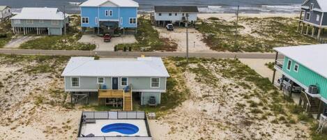 A beachfront property with multiple houses, a swimming pool, and a view of the ocean.