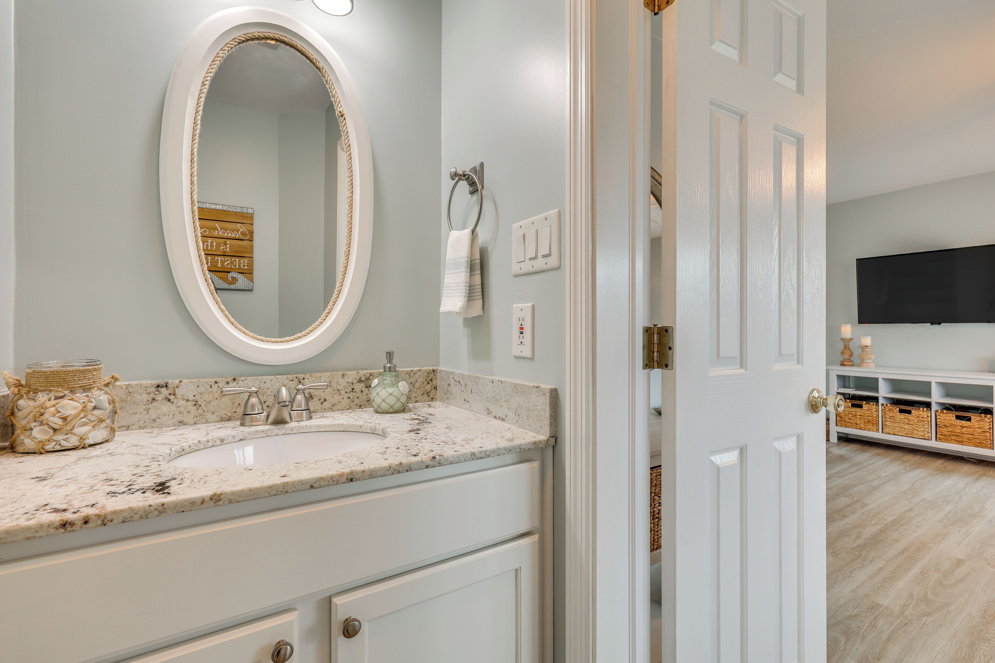 A bathroom with a marble sink, a large mirror, and a towel rack.