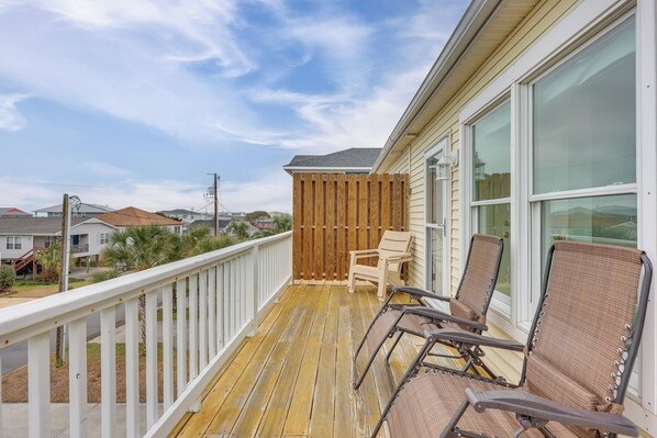 A wooden deck with two chairs and a table, overlooking a residential area.