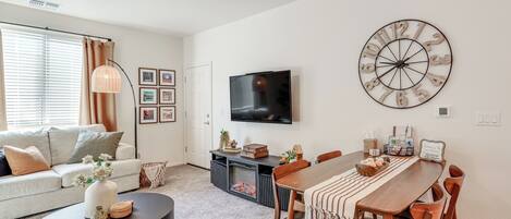 A modern living room with a sofa, coffee table, fireplace, TV, and dining area.