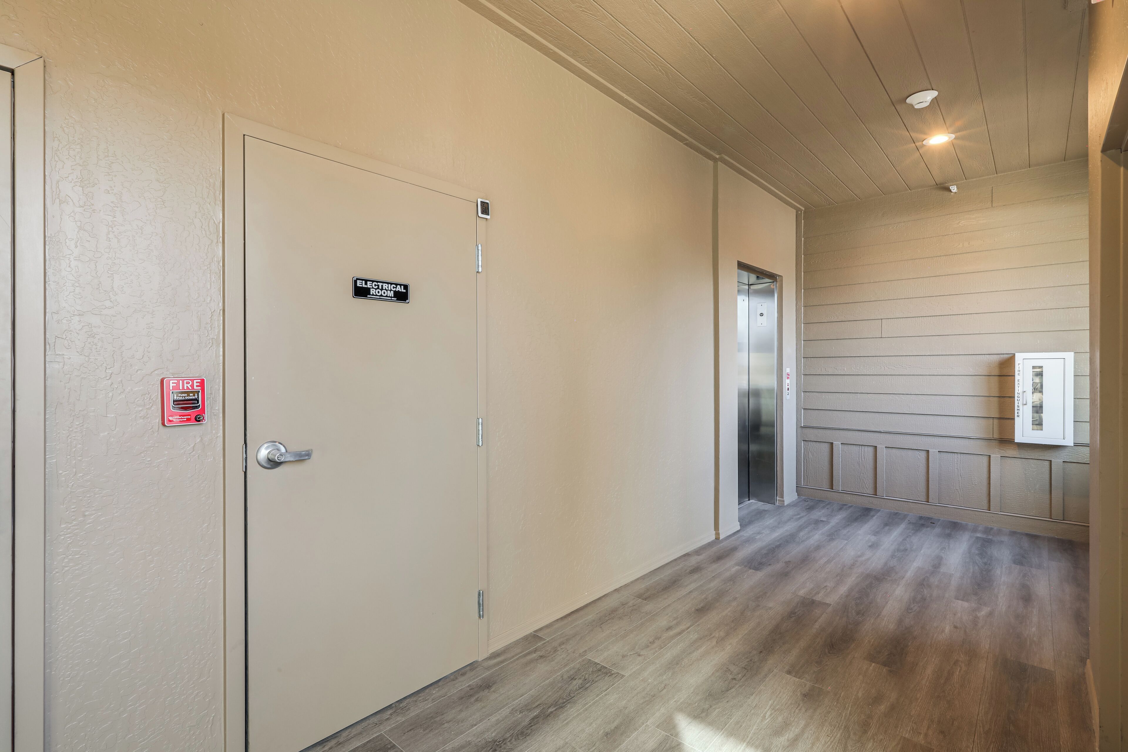 A hallway with a beige door marked "Electrical Room" and a fire alarm.