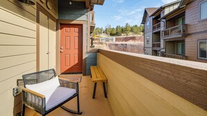 A balcony with a wicker chair, a wooden bench, and a red door. - 1 Mi to Dtwn Flagstaff: Condo w/ 2 Balconies! (Flagstaff)