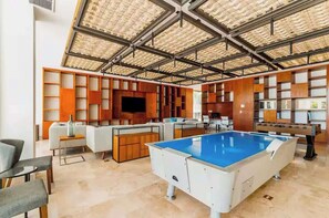 A spacious indoor area with a pool table, seating, and a high ceiling with a grid-like pattern.