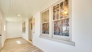 A hallway with wooden flooring, white walls, and large windows with stained glass. - Mountain Views: Peaceful Aguilar Getaway! (Aguilar)
