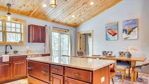 A spacious kitchen with wooden cabinets, a large island, and a dining area with a table and chairs. - 6 Mi to Lake Winnipesaukee: New Hampshire Home (Gilford)