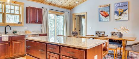 Una cocina amplia con armarios de madera, una isla grande y un comedor con mesa y sillas.