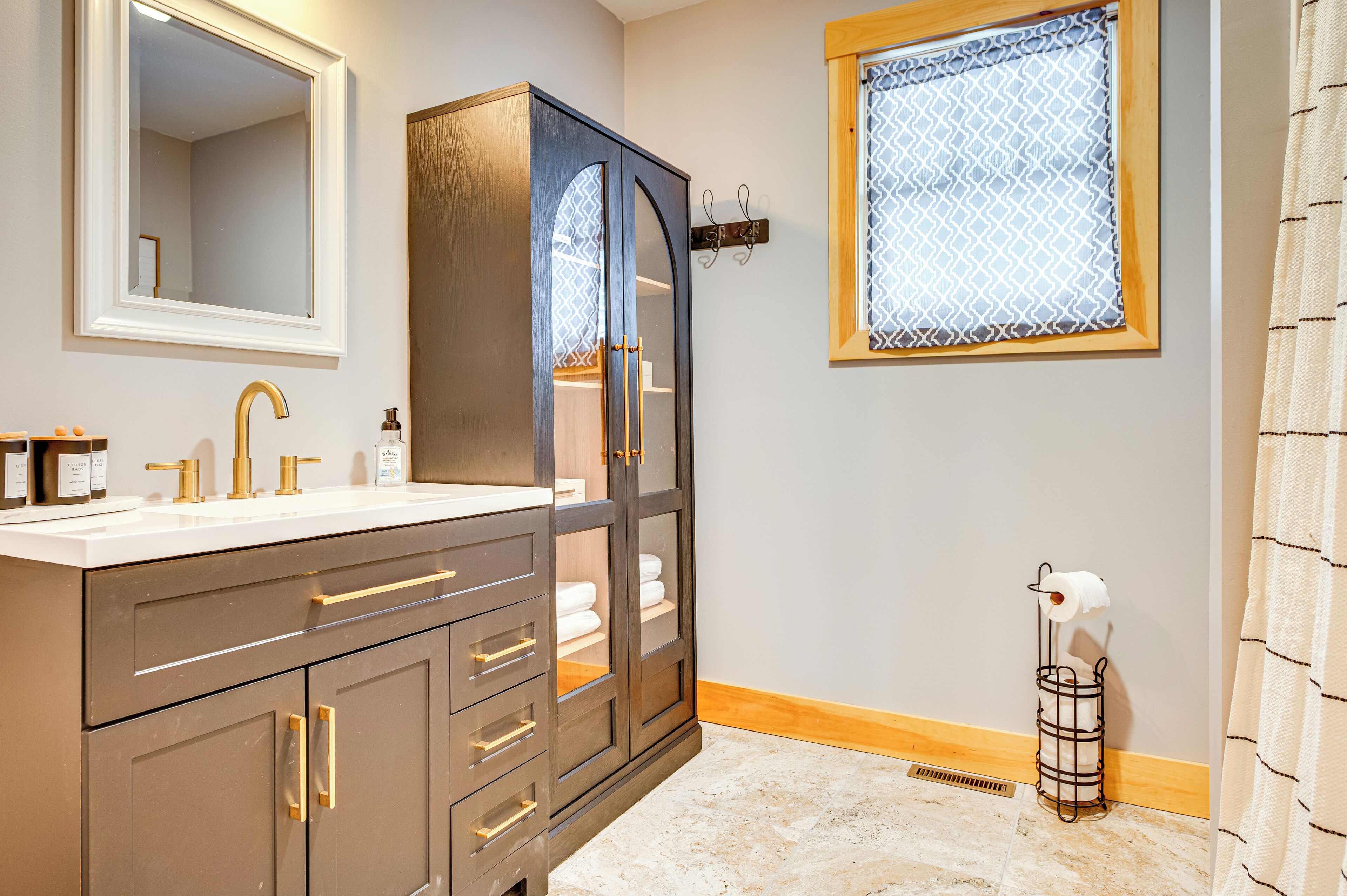 A bathroom with a double vanity, a large mirror, a cabinet with drawers, a towel rack, and a toilet paper holder.