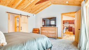 A bedroom with a bed, wooden dresser, and a television. There is a doorway leading to a kitchen area. - 6 Mi to Lake Winnipesaukee: New Hampshire Home (Gilford)