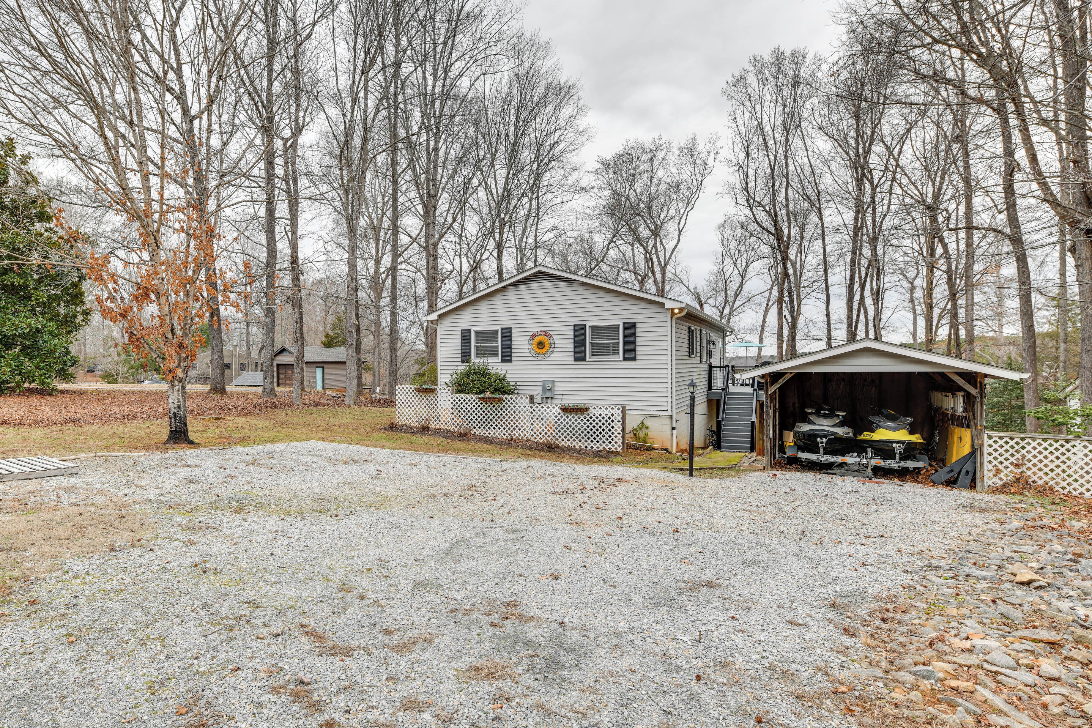 A single-story house with a garage, surrounded by trees and a gravel driveway.