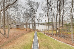 A pathway leading to a lake with houses in the background.