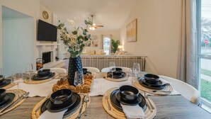 Un coin repas avec une table dressée, une cheminée, un téléviseur et une vue sur l’extérieur.