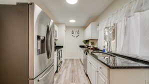 Une cuisine moderne dotée d’appareils électroménagers en acier inoxydable, de meubles blancs et d’un plancher en bois.
