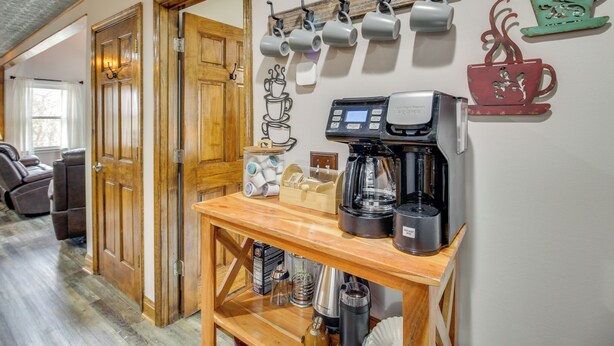 A coffee station with a coffee maker, cups, and a coffee grinder. - Ellijay Mtn Cabin w/ Hot Tub & Community Perks (Ellijay)