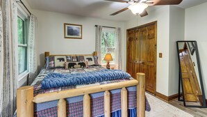 A bedroom with a bed, a ceiling fan, a window with curtains, a wooden door, and a mirror. - Ellijay Mtn Cabin w/ Hot Tub & Community Perks (Ellijay)