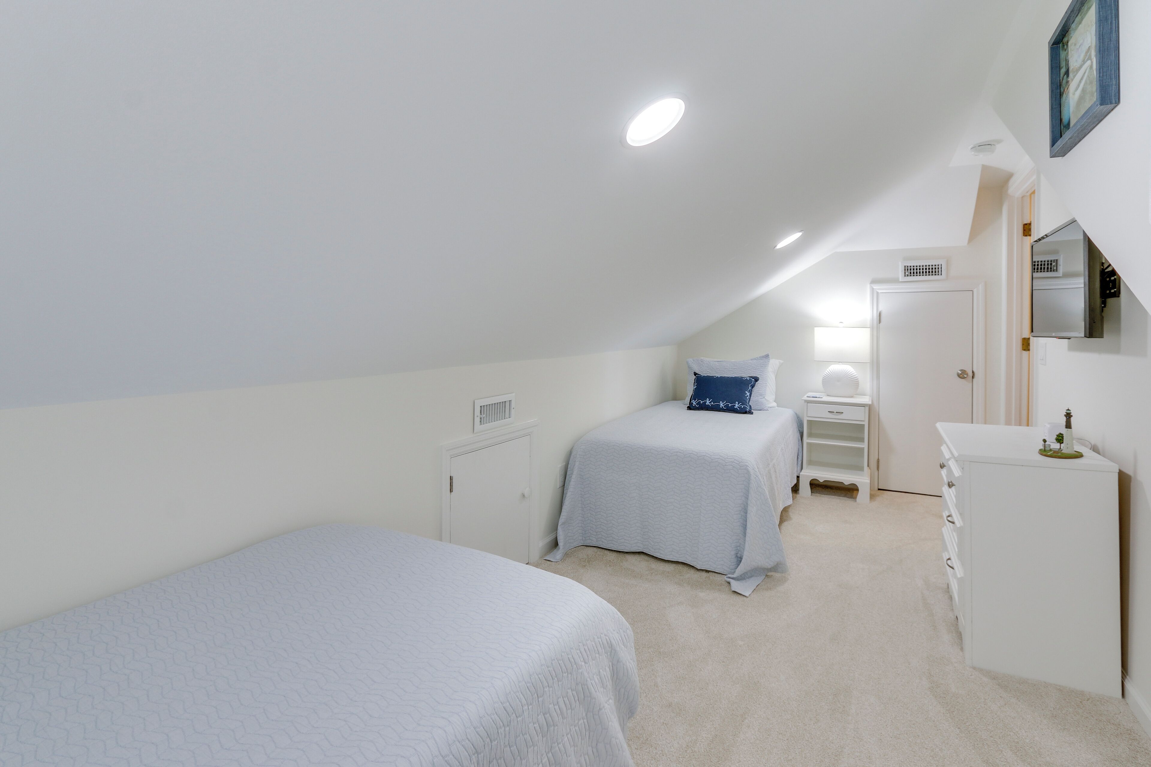 Un dormitorio con dos camas, un tocador, un aparador y una puerta.