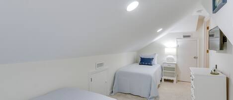 Un dormitorio con dos camas, un tocador, un aparador y una puerta.